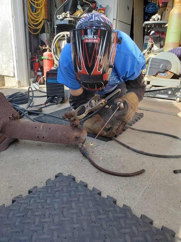 Dave welding a trailer part in his driveway, sparks flying
