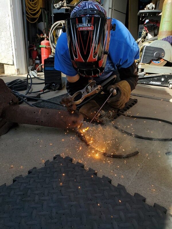 Repairing a rusted boat trailer tongue in the driveway